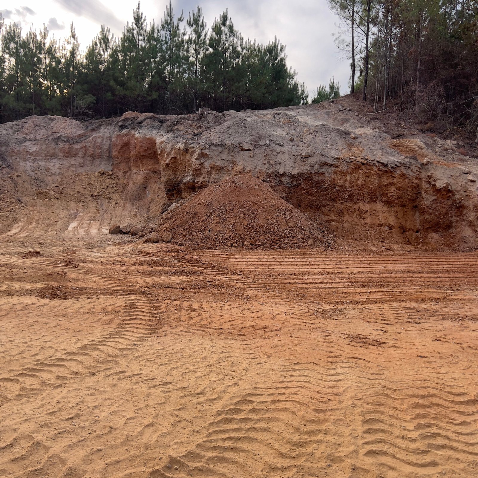 A close-up view of red dirt gravel surface, composed of small, unevenly shaped stones and red dirt varying in size and shade.